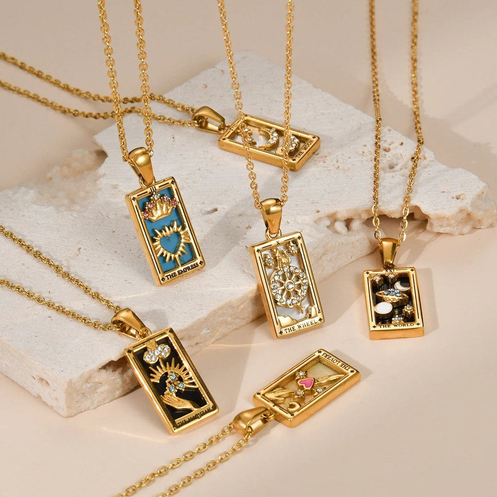 AuraTemple gold stainless steel tarot necklaces with cubic zirconia. Designs include The Empress, The Wheel, The Moon, The Magician, and The Lovers.
