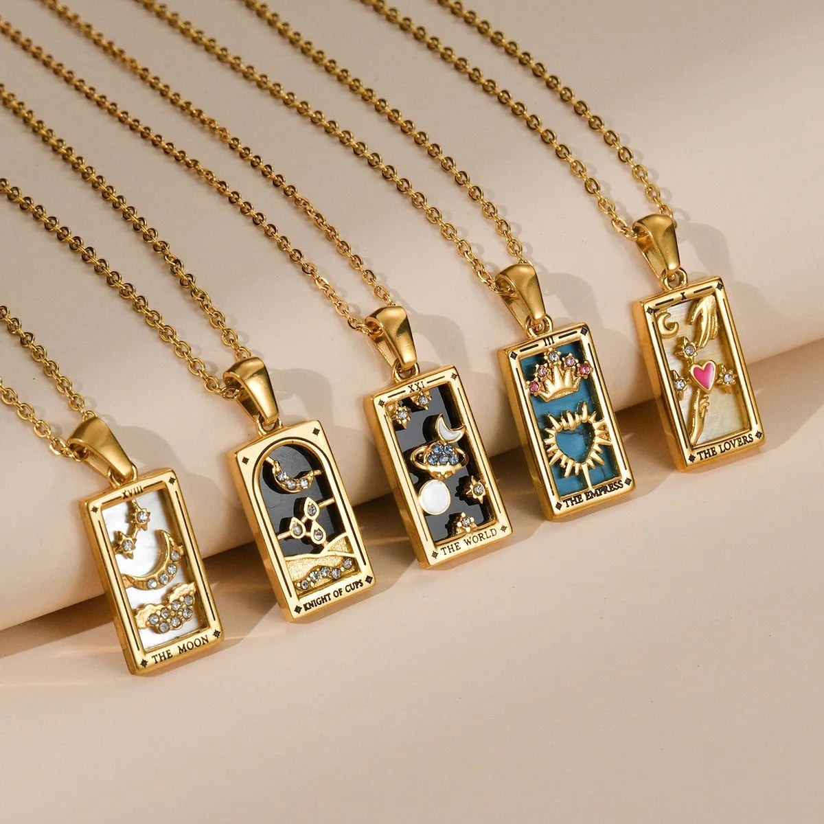 AuraTemple gold stainless steel necklaces featuring tarot card pendants with cubic zirconia. Designs include The Moon, Knight of Cups, The World, The Empress, and The Lovers.