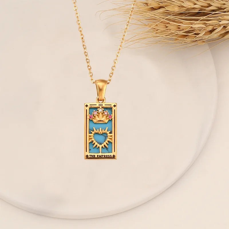 AuraTemple gold necklace with a rectangular pendant featuring a turquoise inlay, a golden crown, and a heart symbol. Accented with small pink and clear cubic zirconia stones.